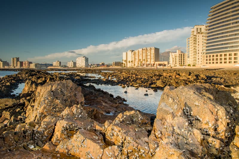 Felsige Küstenlinie der False Bay mit der Stadt im Hintergrund