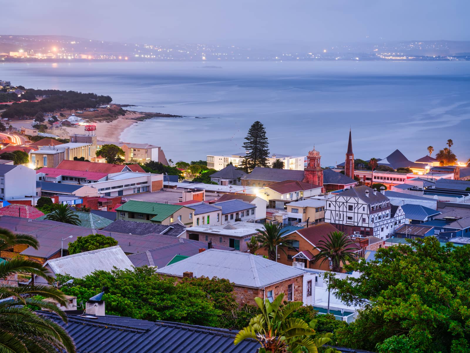 Häuser am Strand von Mossel Bay in der Dämmerung, Lichter entlang der Bucht