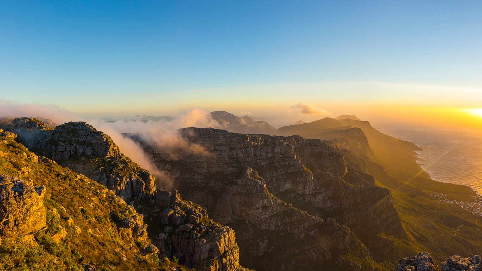 Die Bergkette der Zwölf Apostel im Abendlicht, vom Tafelberg aus gesehen, mit Wolken über den Hängen